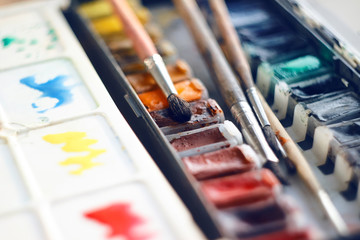 Art set of vintage palette of watercolor paints in cuvettes and several brushes made of squirrel hair, suitable for painting with watercolor paints.