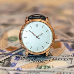 Management efficiency concept of time and money, wrist gold watch and US dollar banknotes.