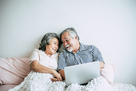 Elderly couples talking and using laptop in bedroom