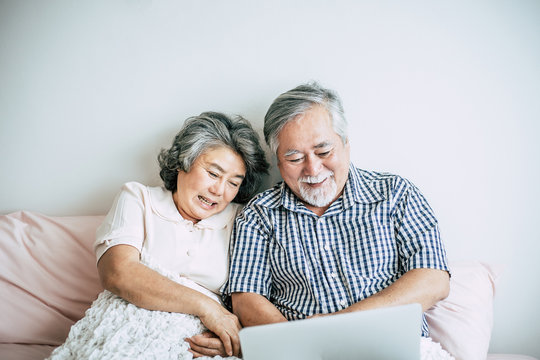 Elderly couples talking and using laptop in bedroom