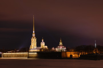 Fototapeta na wymiar Peter and Paul Fortress of St. Petersburg, Russia in the evening or in the night and Neva river covered with the ice and snow in the cloudy weather