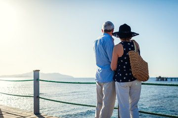 Senior couple walking on pier by Red sea. People enjoying summer vacation.