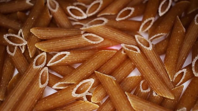 Whole grain pasta healthy food closeup texture video on rolling rotating looping plate