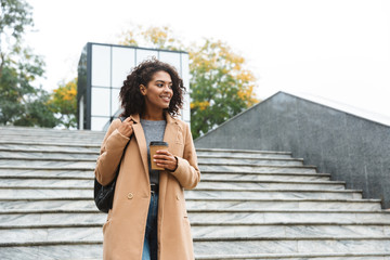 Cheerful young african woman wearing coat walking