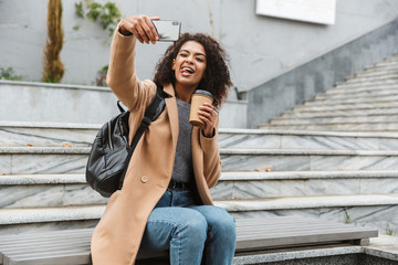 Cheerful young african woman wearing coat walking