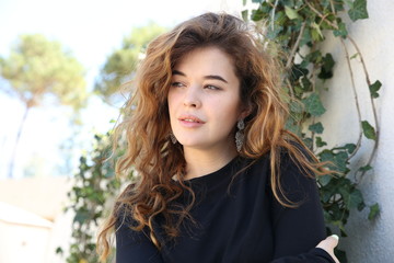 beautiful young happy woman with long hair in a park on a background of greenery
