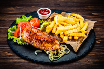 Grilled chicken fillet with french fries on wooden table