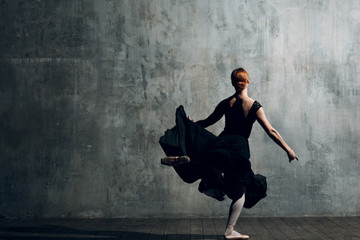 Ballerina female. Young beautiful woman ballet dancer, dressed in professional outfit, pointe shoes and black dress.