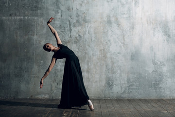 Ballerina female. Young beautiful woman ballet dancer, dressed in professional outfit, pointe shoes and black dress. - obrazy, fototapety, plakaty