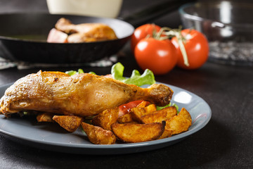 Roasted chicken legs with potato wedges and tomatoes