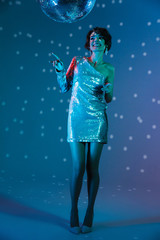 Young happy woman posing isolated with disco ball lights.