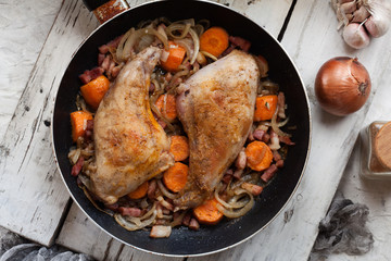 Fried rabbit legs on frying pan with vegetables