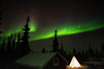 Northern lights (Aurora borealis) with starry sky over the wooden house, Yellowknife, Canada