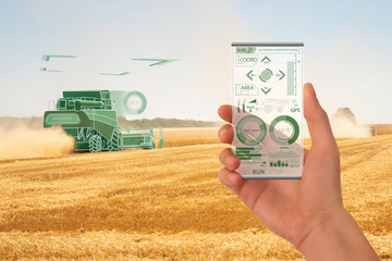 Farmer uses a futuristic smartphone to control autonomous harvester. Smart farming concept