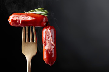 Grilled sausages with rosemary on a fork.