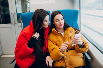 Young females with mobile phone in railway train.