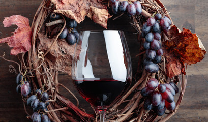 Glass of red wine with grapes and dried  leaves.