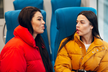 Two girlfriends going to trip by railway train and make faces