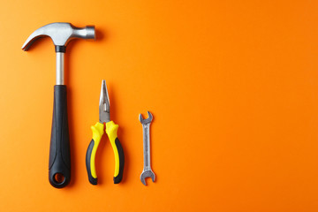 Metal hammer, pliers, a key on an orange background