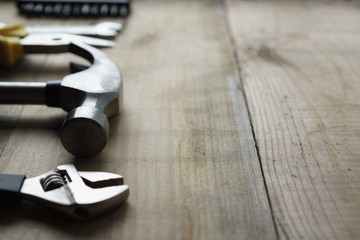 Metal hammer, screwdriver, pliers on a wooden background, side view