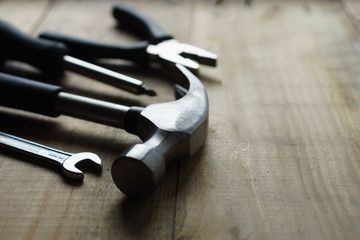 Metal hammer, screwdriver, pliers on a wooden background, side view, close-up