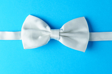 White bow tie on blue background, top view