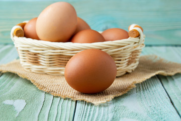 Chicken eggs in a basket on a wooden table, side view