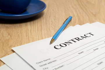 Contract with pen and notebook on wooden table.