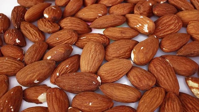 Whole almond almonds nut nuts closeup texture video on rolling rotating looping plate
