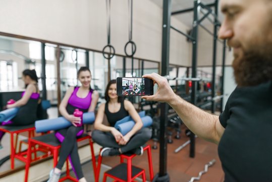 Young athletic smiling woman laughing in the gym, photographed on mobile phone. Fitness, sport, training, people, healthy lifestyle concept.