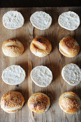 Sesame burgers buns split in half on wooden cutting board top view. Cooking process