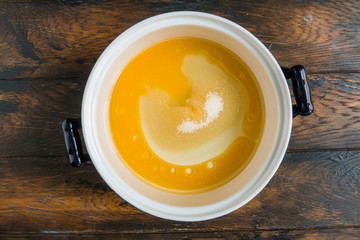 Dough making, olive oil, sugar and orange juice in white bowl. Wooden rustic table, top view