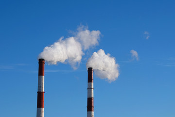 Environmental problem of environmental pollution and air in large cities. Pipes in city with smoke, against a blue sky background.