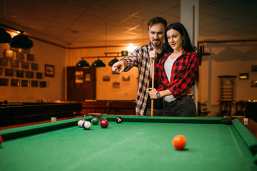 Male and female billiard players with cue