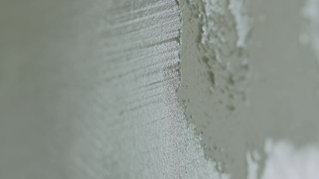Slow motion closeup worker applying decorative concrete plaster on the wall