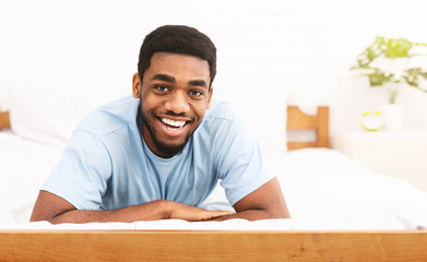 Portrait of smiling young black man on bed - Powered by Adobe