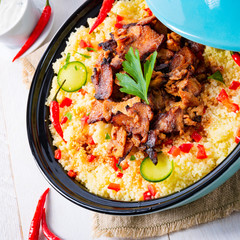 Tajin with couscous, vegetables and meat on white background