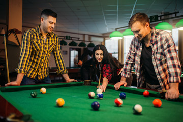 Billiard players with cues at the table with balls