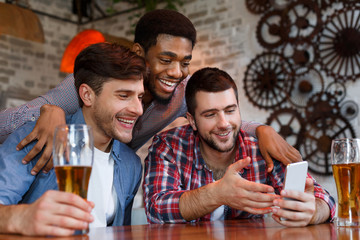 Men watching videos on smartphone and drinking beer