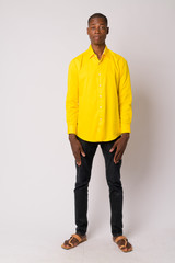 Full body shot of young handsome bald African businessman wearing yellow shirt