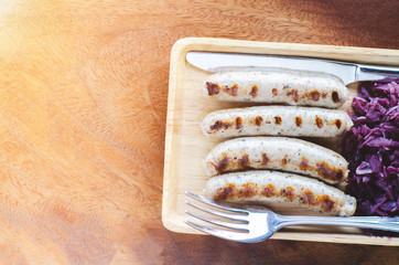 Pork sausage, purple pickles and sauces on wooden dishes at the morning restaurant.