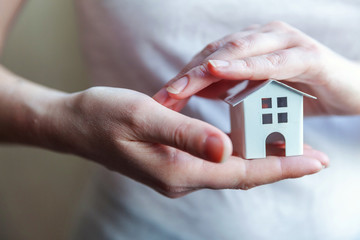 Female woman hands holding small miniature white toy house. Mortgage property insurance dream moving home and real estate concept