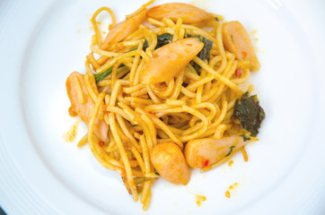 Spaghetti with sausage, Stir-fried sausage, Italian food.Spaghetti with red sauce, white plate on the table in the morning restaurant.