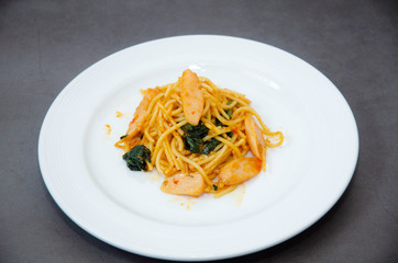 Spaghetti with sausage, Stir-fried sausage, Italian food.Spaghetti with red sauce, white plate on the table in the morning restaurant.