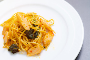 Spaghetti with sausage, Stir-fried sausage, Italian food.Spaghetti with red sauce, white plate on the table in the morning restaurant.