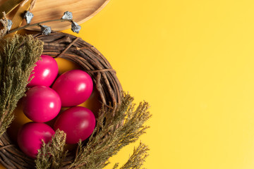 easter eggs pink colorful food kitchen with vine wood and dried flower on yellow background in top...