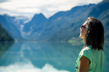 Portrait of young, beautiful woman standing near by mountain lake in Norway.