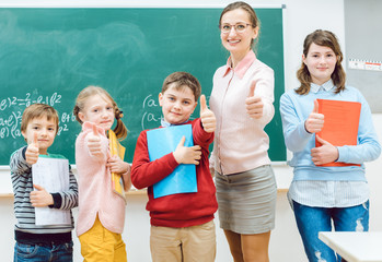Pupils and teacher showing thumbs-up in school having fun