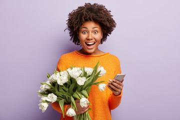 Smiling emotional female celebrates birthday, gets message of congratulation and flowers from...