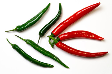 Green and red chili peppers on white background, top view. Hot spicy food symbol.